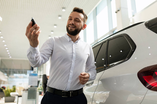 homem confiante com chaves para um carro novo em uma concessionária de carros - Foto, Imagem