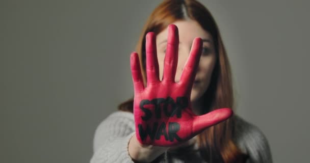 Chica joven se rebela contra la guerra y dice que pare con la mano roja escrita - Metraje, vídeo