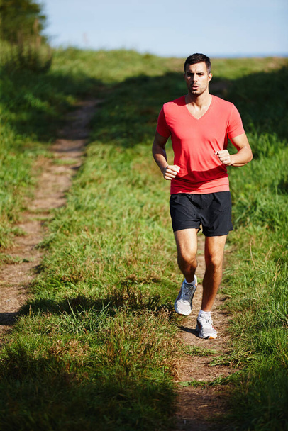Proper breathing is important when running. Shot of a handsome young man taking a jog outdoors. - Foto, imagen