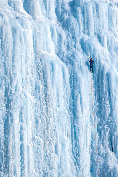 El escalador de hielo sube a la pared vertical. Los atletas disfrutan del aire libre escalando la pared de hielo. Gente activa disfrutando de deportes de adrenalina. - Foto, Imagen
