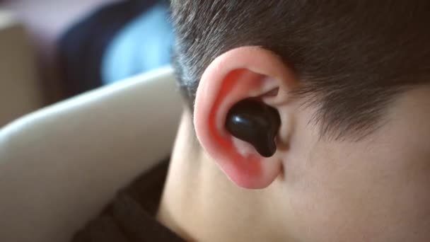 ein Teenager hat ein Bluetooth-Headset im Ohr und hört Musik, Nahhörer und Ohr, - Filmmaterial, Video