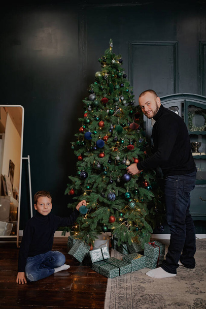 Πατέρας και γιος κοντά στο χριστουγεννιάτικο δέντρο. Ημέρα του Πατέρα. - Φωτογραφία, εικόνα
