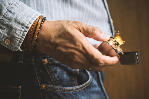 The man sparking his brushed chrome lighter with windproof. - Photo, image