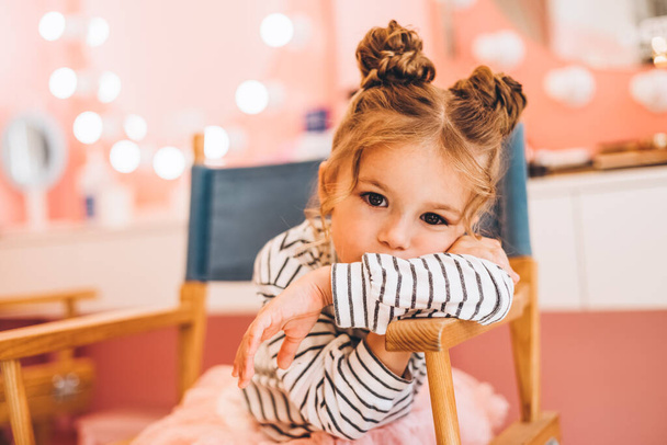 Stylish little girl in a beauty salon for children where she made a beautiful hairstyle. Beauty and kid fashion with healthy hair. - Фото, зображення