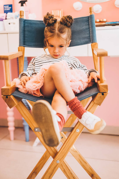 Stylish little girl in a beauty salon for children where she made a beautiful hairstyle. Beauty and kid fashion with healthy hair. - Fotografie, Obrázek
