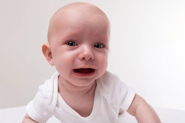 ребенок крупным планом на белом фоне плачет - Фото, изображение