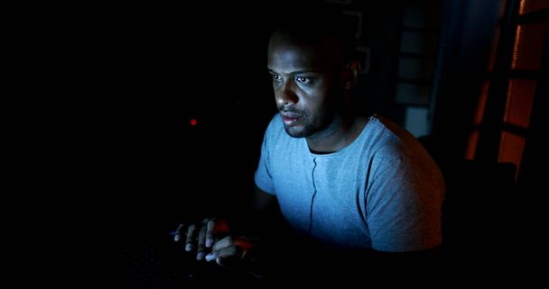 Чоловік працює пізно вночі на комп'ютерному ноутбуці в темряві
 - Фото, зображення