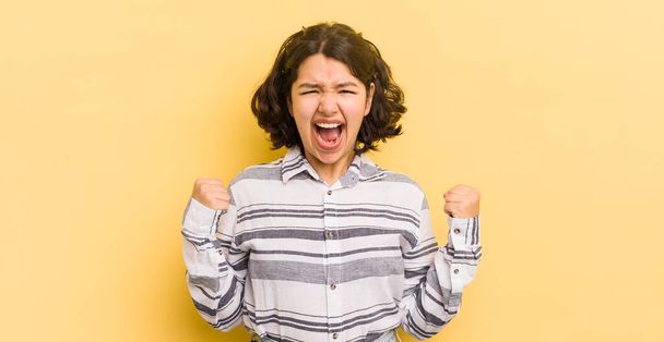 怒りの表情で積極的に叫んでいるか成功を祝う拳で叫んでいるかなりヒスパニックな女性 - 写真・画像