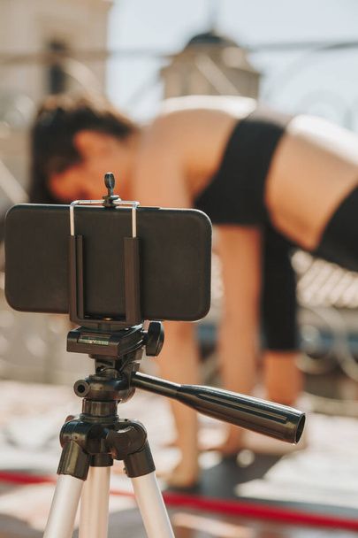 Νεαρή αθλητική fit γυναίκα προπονητής κάνει online μαθήματα μέσω βιντεοκλήσης στο κινητό της τηλέφωνο Μεταδίδει μαθήματα και την έννοια του τρόπου ζωής υγειονομικής περίθαλψης - Φωτογραφία, εικόνα