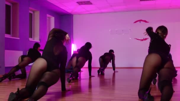 Nők csoportja fekete ruhában táncol stúdióban lila világítással - Felvétel, videó