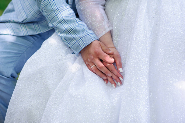 De bruidegom houdt de hand van de bruid vast. De man houdt de hand van het meisje vast. Bruiloft - Foto, afbeelding