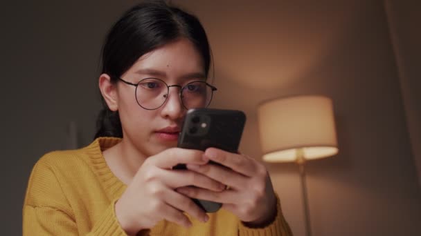 Fiatal nő használ egy okostelefon chat és vásárlás online otthonról Során COVID-19 pandemic.  - Felvétel, videó