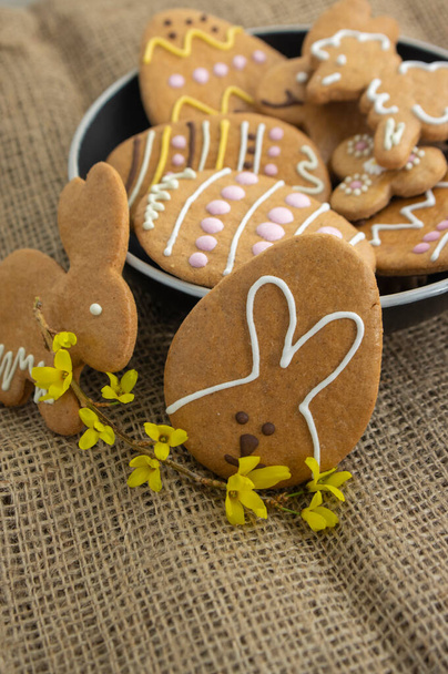 Easter holiday cookies servet on dish on the table with jute tablecloth, group of color painted gingerbread sweets, spring holidays tasty decoration - Fotografie, Obrázek