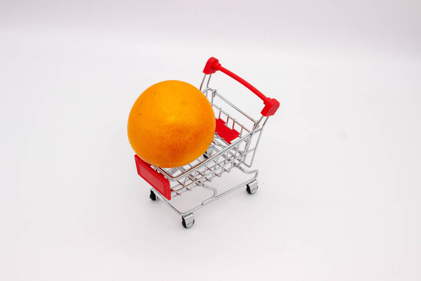 Orange dans le panier en métal du magasin sur fond blanc - Photo, image