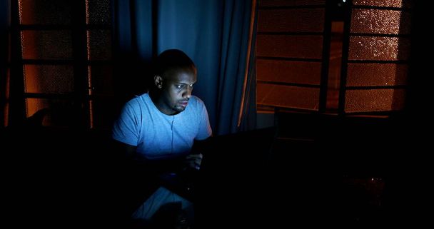Африканський чоловік переглядає Інтернет пізно вночі під час потемніння. - Фото, зображення
