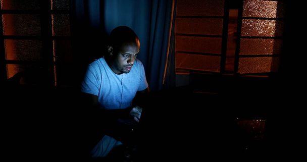 African man browsing internet late at night in pitch dark - Foto, Imagen