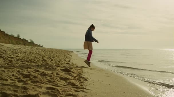 Klein meisje dat buiten speelt op zonsondergang strand. gelukkig kind ontspannen alleen aan zee - Video
