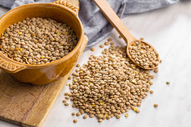 Uncooked brown lentils. Raw legume in bowl on a kitchen table. - Foto, Imagem