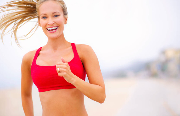 Courir est un mode de vie. Prise de vue d'une jeune femme jogging près de la plage. - Photo, image