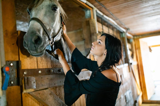 Κορίτσι με μακριά μαύρα μαλλιά στην εξοχή. Ipadrome με άλογα. Αγροτικά τοπία, άγρια δύση. - Φωτογραφία, εικόνα