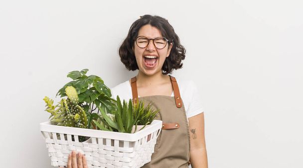 pretty hispanic girl shouting aggressively, looking very angry. plants concept - Foto, Bild
