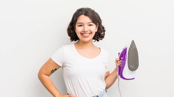 pretty hispanic girl smiling happily with a hand on hip and confident. laundry concept - Fotoğraf, Görsel