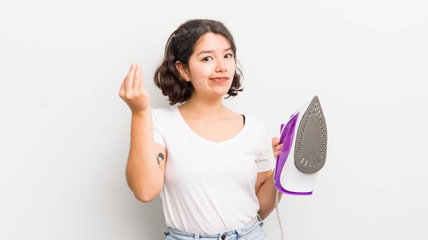 pretty hispanic girl making capice or money gesture, telling you to pay. laundry concept - Foto, imagen