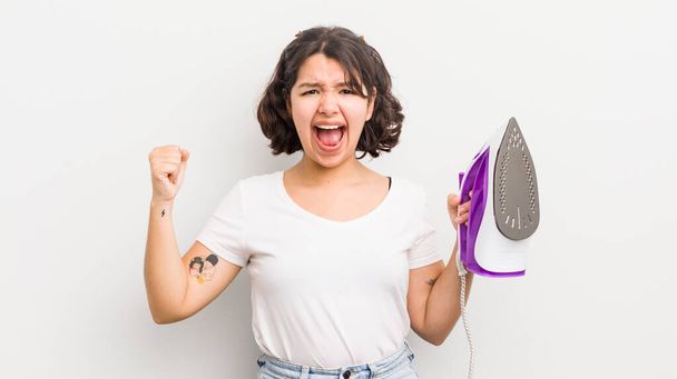 pretty hispanic girl shouting aggressively with an angry expression. laundry concept - Fotoğraf, Görsel
