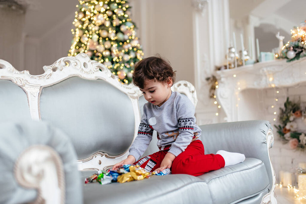 Little boy opens New Year's gifts. Christmas. - Fotó, kép