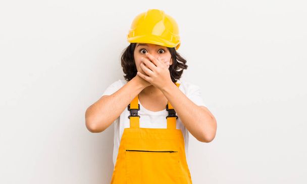 pretty hispanic girl covering mouth with hands with a shocked. worker concept - Foto, Imagem