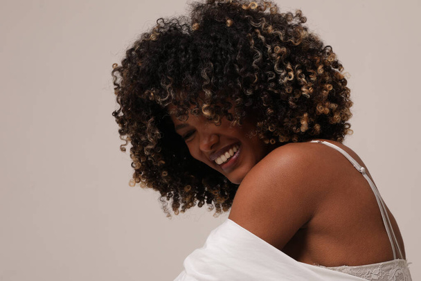 Side view of joyful woman with afro hair smiling over white background. - 写真・画像