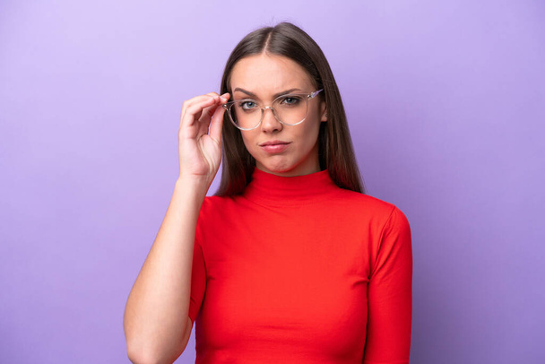 Young caucasian woman isolated on purple background With glasses and frustrated expression - Fotoğraf, Görsel