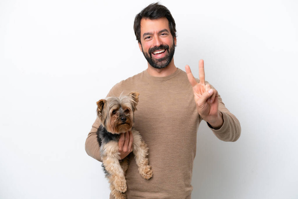 Man holding a yorkshire isolated on white background smiling and showing victory sign - Foto, Imagem