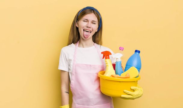 redhead pretty girl with cheerful and rebellious attitude, joking and sticking tongue out. housekeeper concept - 写真・画像