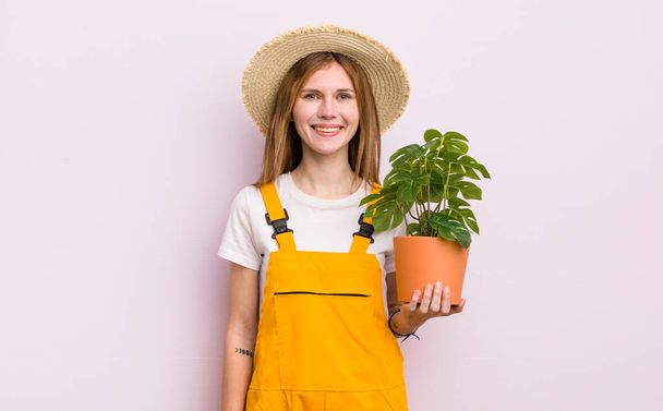 redhead pretty girl smiling happily with a hand on hip and confident. plant and gardering concept - Фото, зображення