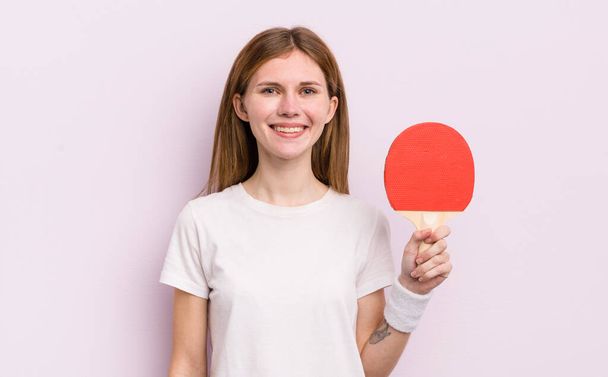 Kızıl saçlı güzel kız mutlu bir şekilde gülümsüyor, eli kalçasında ve kendinden emin. ping pong konsepti - Fotoğraf, Görsel