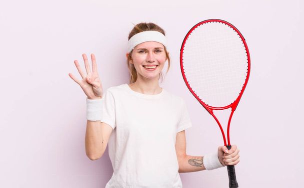 redhead pretty girl smiling and looking friendly, showing number four. tennis concept - 写真・画像