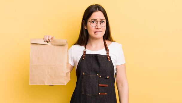 young pretty woman looking puzzled and confused. fast food courier - Foto, Imagen
