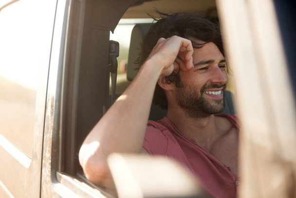 Sin preocupaciones en la carretera. Un joven sonriendo y riendo en un viaje por carretera. - Foto, Imagen