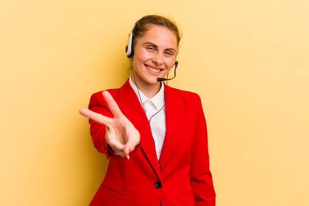 young pretty woman smiling and looking happy, gesturing victory or peace. telemarketer concept - Φωτογραφία, εικόνα