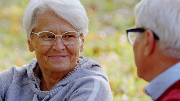 Mujer jubilada de 70 años sonriendo, y hablando con su marido. Al aire libre tiro de cerca. - Foto, Imagen