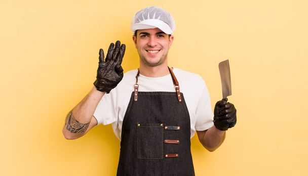 young handsome man smiling and looking friendly, showing number four. butcher concept - Fotoğraf, Görsel