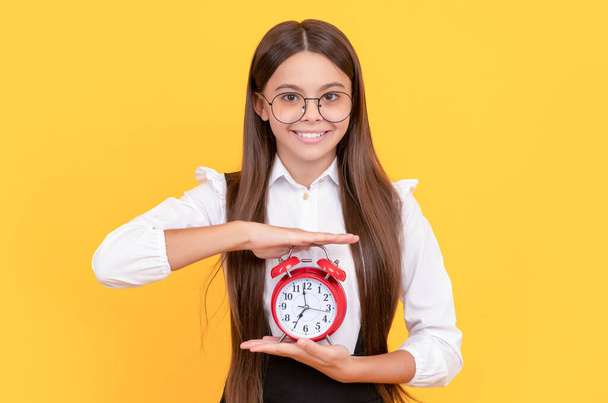 happy kid in school uniform and glasses with alarm clock showing time, school time. - Photo, Image