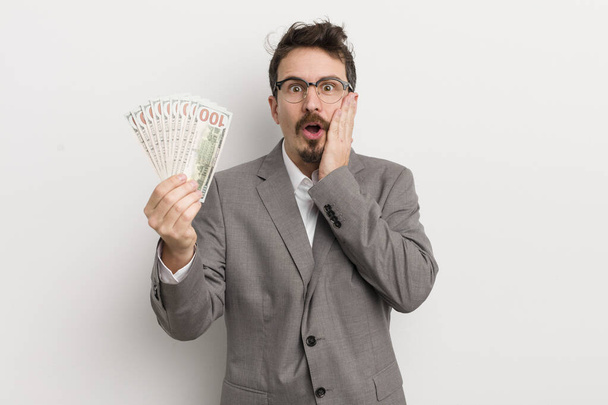 young handsome man feeling shocked and scared. businessman and banknotes - Foto, Bild