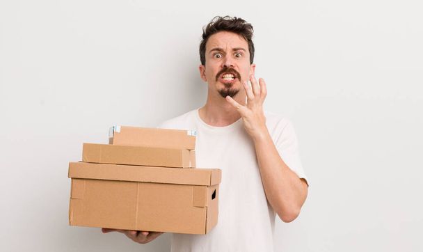 young handsome man looking desperate, frustrated and stressed. shipping boxes concept - Fotoğraf, Görsel