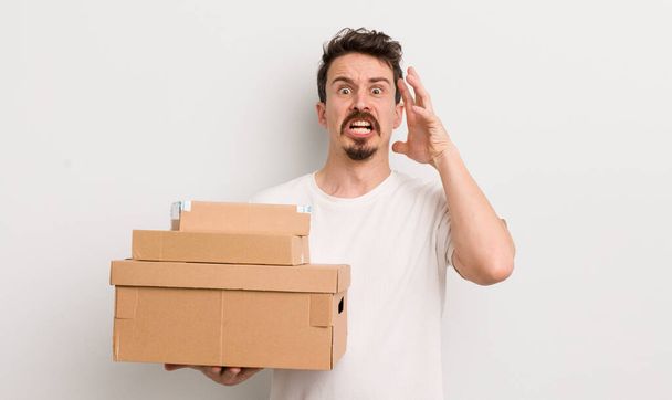 young handsome man screaming with hands up in the air. shipping boxes concept - Fotoğraf, Görsel