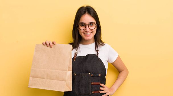 young hispanic woman smiling happily with a hand on hip and confident. fast food deliver concept - Foto, Imagem