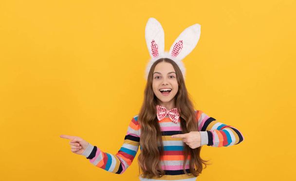 happy easter teen girl in bunny ears and bow tie pointing finger on copy space. - Фото, зображення