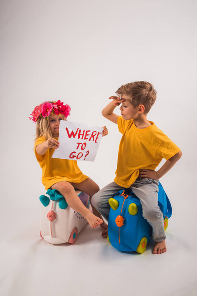Full size photo of funny relaxing boy and girl sitting on baggag - 写真・画像