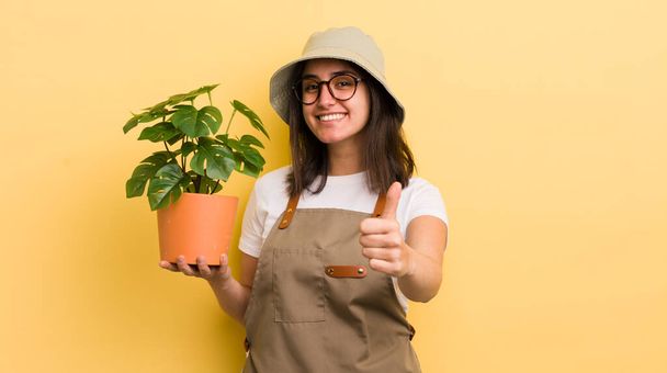 young hispanic woman feeling proud,smiling positively with thumbs up. gardener and plant concept - Fotografie, Obrázek